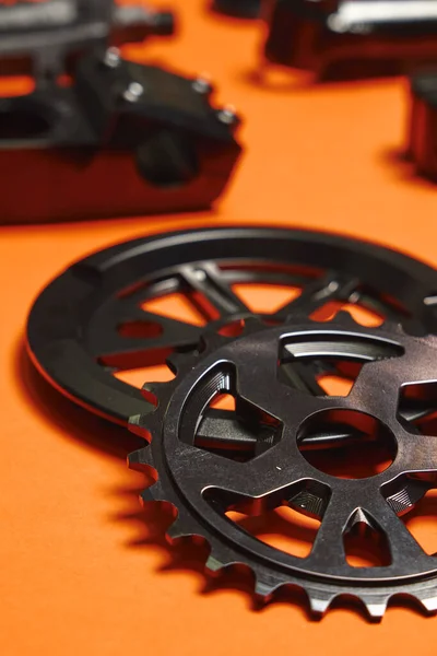 The gear of a BMX bike lies on an orange background. Different parts for extreme bike. Minimalism.