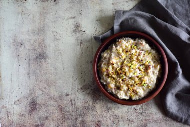 Sütlü sıcak yulaf lapası. Gri arkaplanda kil tabakta yulaf ezmesi.
