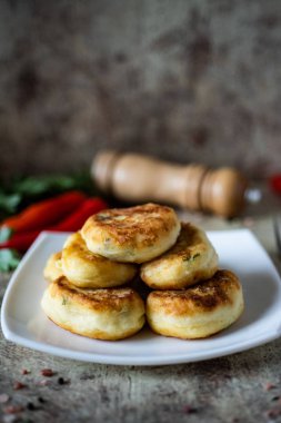 Vejetaryen yemeği: beyaz tabakta peynirli patates pirzolası. Dikey fotoğraf