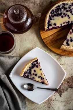 Tahta tabakta yabanmersinli turta, beyaz tabakta bir parça yabanmersinli turta ve güzel gri arka planda bir fincan sıcak çay.