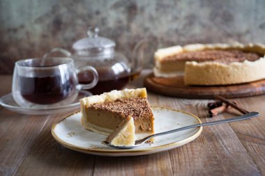 Eski ahşap bir arka planda kaşıkla güzel beyaz bir tabakta çikolata parçalı lezzetli bir balkabağı turtası.