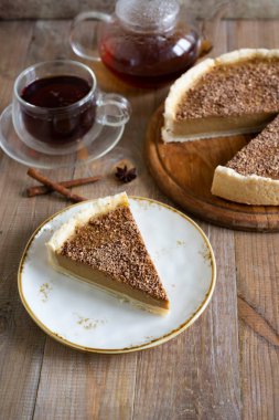 Bir parça lezzetli balkabaklı cheesecake, güzel bir tabakta çikolata ve bir fincan kokulu çay. Dikey fotoğraf