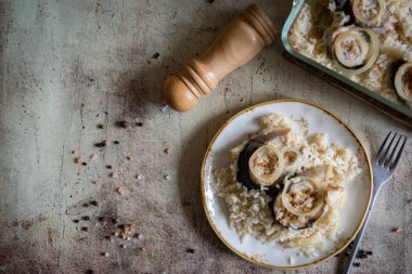Sıcak bir öğle yemeği: beyaz tabakta balık ve pilav. Mackerel, gri arka planda eski bir tabakta pilavla pilav pişiriyor..
