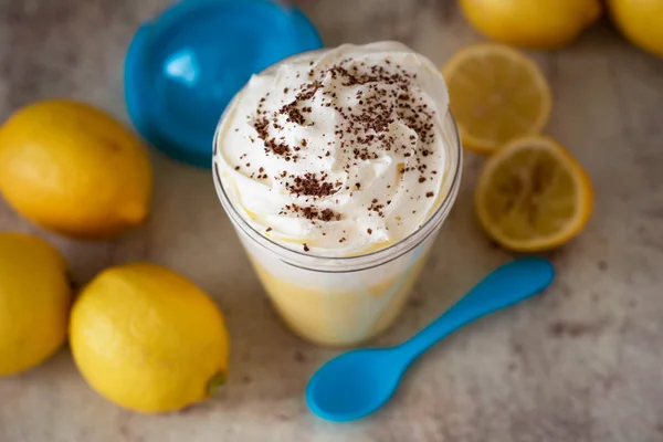 Lemon dessert with whipped cream. Delicate citrus mousse with whipped cream and chocolate in a transparent jar