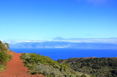 La Gomera 'daki Agulo' daki Mirador de Abrante 'de volkanik kökenli renkli kırmızı toprak ve kum tepeleri Tenerife' deki Teide volkanı ile Atlantik Okyanusu 'nun kuzeyine bakıyor.
