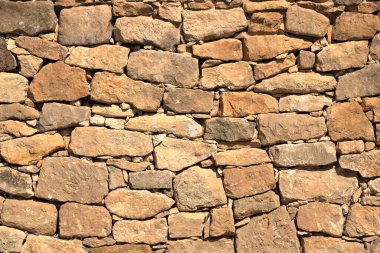 Taş tuğlalardan yapılmış büyük sarı duvar.