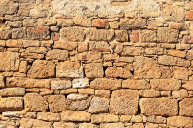 Taş tuğlalardan yapılmış büyük sarı duvar.