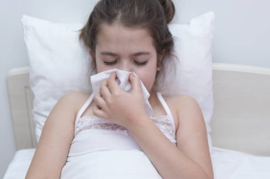 Mendil kullanan genç bir kız. Çok yaşayın. Evde hastalığıyla uğraşırken kanepede mendil kullanan küçük tatlı bir kız.