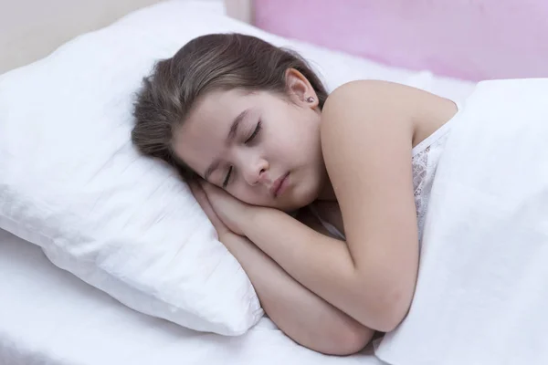 Sleeping child in white bedding room for copy space. Healthy sleep tips. Girl sleep on little pillow bedclothes background.Kid long curly hair fall asleep pillow close up. Choose proper pillow to relax.Cute pillow and bedclothes for childish bedroom.