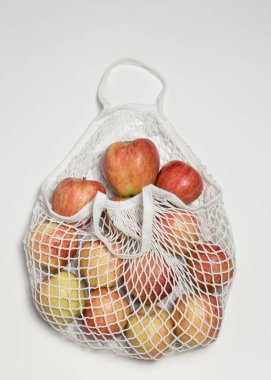 Elmalı, beyaz arkaplan, taze meyve, beyaz ip torbalı, tekrar kullanılabilir pamuk telli taşınabilir el çantası. Yeniden kullanılabilir sıfır atık tekstil torbası, beyaz arkaplanda üst görünüm. 
