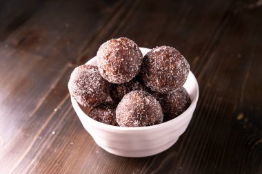 Tarih, ceviz, badem ve hindistan cevizli ev yapımı enerji topları. Sağlıklı tatlı yiyecekler. Uzay enerji toplarını beyaz bir arka planda bir kaseye kopyala. Ham enerji topları, tüm doğal ve sağlıklı ham enerji ısırıkları.