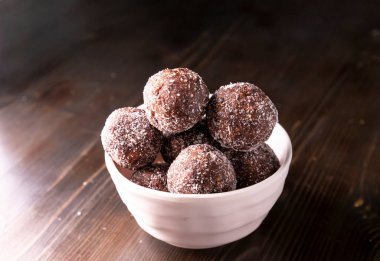 Tarih, ceviz, badem ve hindistan cevizli ev yapımı enerji topları. Sağlıklı tatlı yiyecekler. Uzay enerji toplarını beyaz bir arka planda bir kaseye kopyala. Ham enerji topları, tüm doğal ve sağlıklı ham enerji ısırıkları.