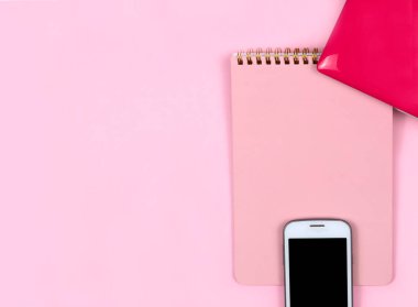 Ev ofisinin masası düzdü. Dizüstü bilgisayarlı kadın çalışma alanı, pembe arka planlı telefon defteri. Üst görünüm kadınsı arka plan. Serbest meslek kavramı. Fotokopi alanı olan üst görünüm, düz yatay fotoğraf.