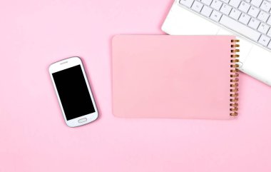 Ev ofisinin masası düzdü. Dizüstü bilgisayarlı kadın çalışma alanı, pembe arka planlı telefon defteri. Üst görünüm kadınsı arka plan. Serbest meslek kavramı. Fotokopi alanı olan üst görünüm, düz görüntü. Çalışma masasının yaratıcı düz yatay fotoğrafı.