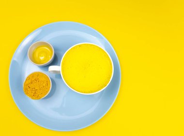 Zerdeçal latte, altın latte, sarı arka planda sıcak ve sağlıklı bir içecek. Üst Manzara. Yakın plan. Kopyalama alanı. Bağışıklık arttırıcı, iltihaplanma önleyici sağlıklı içecek.