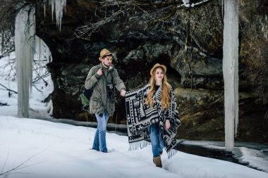 Bir çift kâşif, kış dağlarındaki vadi ve kayaların arka planında..