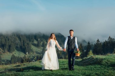 Güzel bir dağ manzarasının arka planında bir gelin ya da bir çift ile damat. Dağlık bölgede düğün.