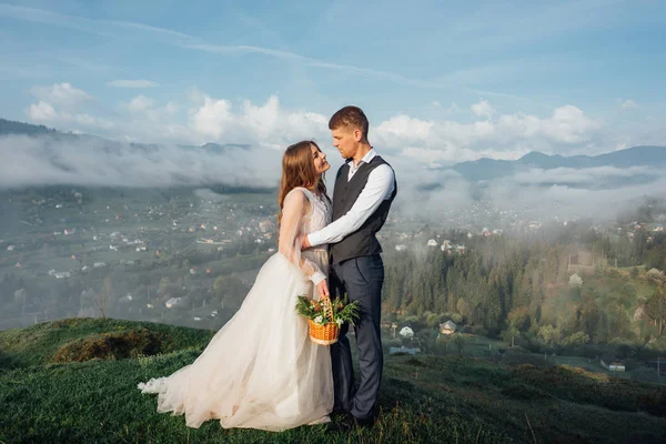 Schönes Hochzeitspaar posiert auf Hügeln im Nebel — Stockfoto