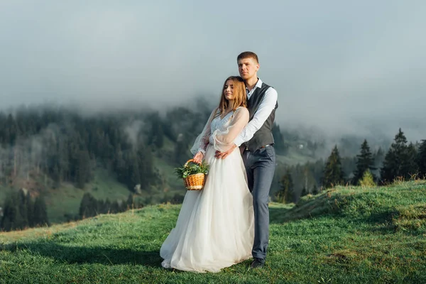 Schönes Hochzeitspaar posiert auf Hügeln im Nebel — Stockfoto