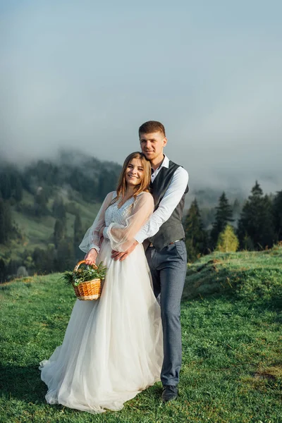 Güzel bir dağ manzarasının arka planında bir gelin ya da bir çift ile damat. Dağlık bölgede düğün. — Stok fotoğraf