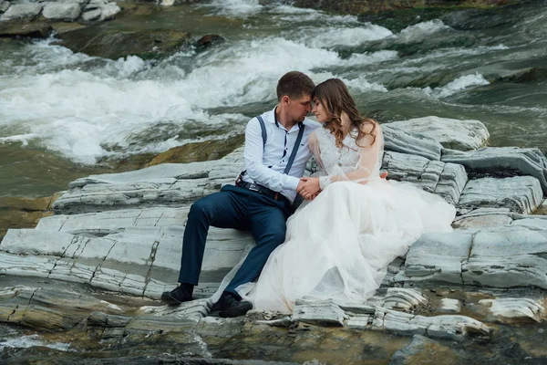 Düğün çifti dağ nehrinin yanında kucaklaşıyor. Damat ve gelin. Doğa düğün fotoğrafı.. — Stok fotoğraf