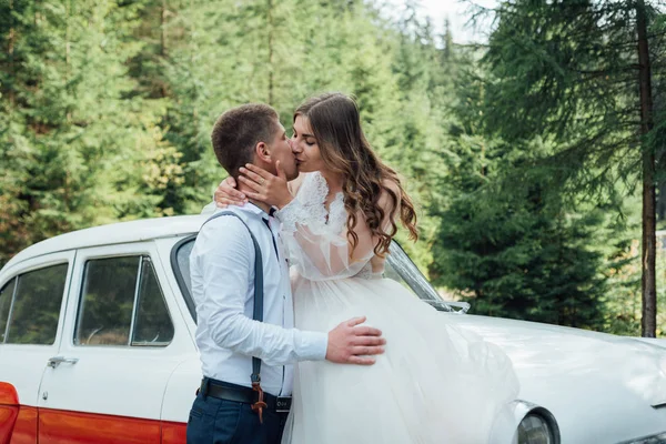 Novia y novio en el bosque cerca de coche de boda de lujo —  Fotos de Stock