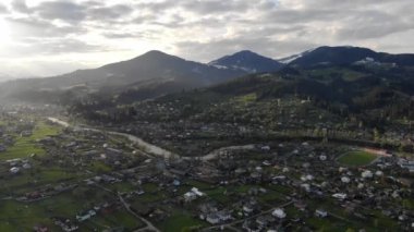 Hava Aracı Görüntüsü: Bahar Dağı köyü üzerinde günbatımında yumuşak ışıkta ormanla birlikte uçuş. Karpat Dağları, Ukrayna, Avrupa. Muhteşem bir manzara. Güzellik.