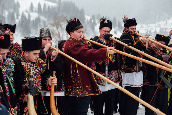 Kryvorivnia, Ukraine - January 7, 2019: Famous hutzulian Koliadnyky of Kryvorivnia singing Christmas carols and playing on traditional trembita horn. . Old winter holiday traditions of Carpathian .