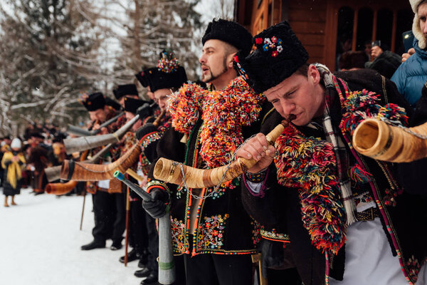 Kryvorivnia, Ukraine - January 7, 2019: Famous hutzulian Koliadnyky of Kryvorivnia singing Christmas carols and playing on traditional trembita horn. . Old winter holiday traditions of Carpathian .