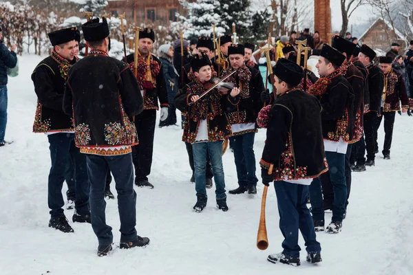 Kryvorivnia, Ucrania - 7 de enero de 2019: Famoso hutzulian Koliadnyky de Kryvorivnia cantando villancicos y marchando alrededor de una antigua iglesia de madera. Antiguas tradiciones invernales de las montañas Cárpatas . — Foto de Stock
