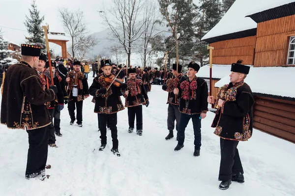 Kryvorivnia, Ucrânia - 7 de janeiro de 2019: Famoso hutzulian Koliadnyky de Kryvorivnia cantando canções de Natal e marchando ao redor da antiga igreja de madeira. Velhas tradições de inverno das montanhas dos Cárpatos . — Fotografia de Stock