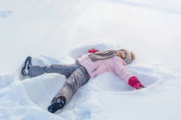 Cute girl plays with snow in winter.