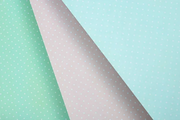 Colored paper background. delicate pastel color, mint green, blue and pink in white polka dots. diagonally