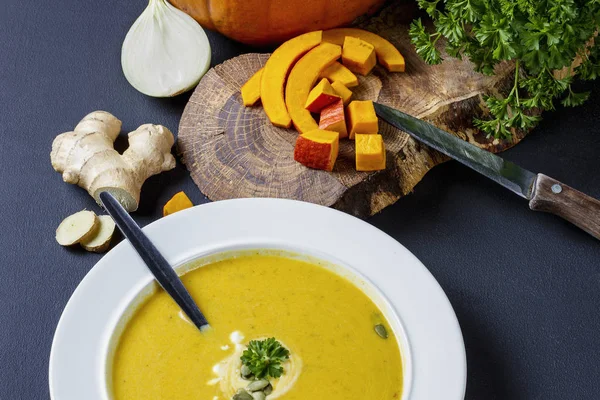 Pompoensoep met room en zaden, met ingrediënten in de achtergrond — Stockfoto