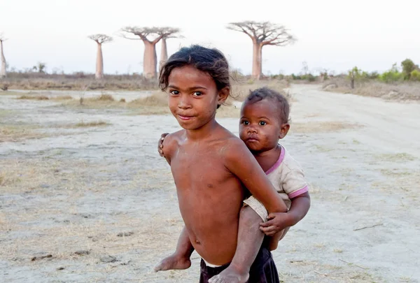 Madagascar-shy and poor african girl with infant on her back - poverty