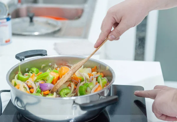 Chef preparing cook vegetables frying on pan with a lot of white smoke in the kitchen