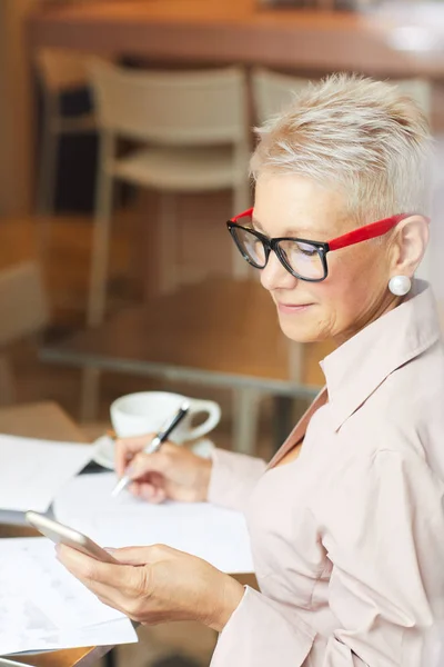 Mujer Negocios Madura Seria Gafas Mirando Teléfono Móvil Tomando Notas —  Fotos de Stock