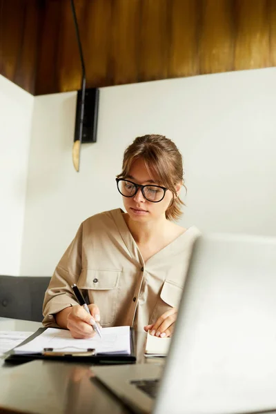 Koncentrerad Ung Affärskvinna Med Glasögon Sittande Vid Bordet Framför Laptop — Stockfoto