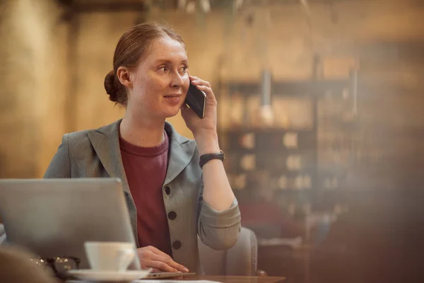 Fiatal Üzletasszony Beszél Mobiltelefonon Miközben Dolgozik Asztalnál Laptop Kávézóban — Stock Fotó