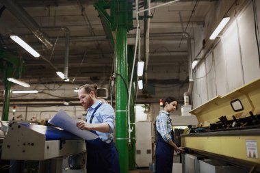 Baskı fabrikasındaki torna işleriyle meşgul iki işçi.