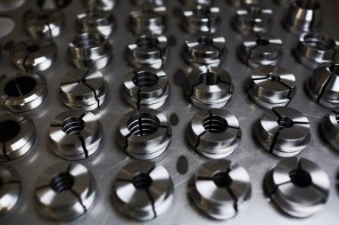 Fabrikada yeni metal vidalar üretilen metal panelin yakın çekimi.