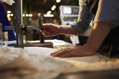 Close-up of manual worker standing near the lathe and working producing details in the plant