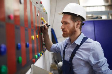 Foreman in work wear standing near the blackboard and making the timetable of workers