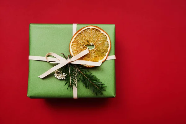 포장지 장식을 전나무 가지에 크리스마스 선물붉은 오렌지를 — 스톡 사진