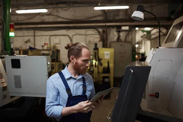 공장에서 원격으로 태블릿 기계를 사용하여 작업대에서 노동자 — 스톡 사진