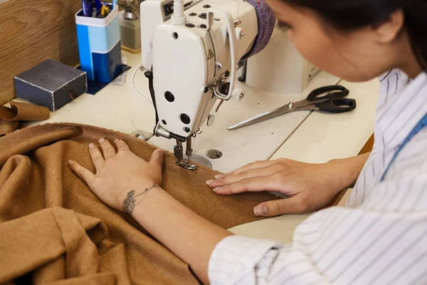 Zbliżenie Młodej Kobiety Szyjącej Ubrania Brązowego Materiału Włókienniczego Pomocą Maszyny — Zdjęcie stockowe