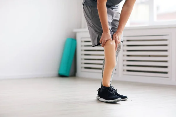 Young man wearing prosthesis on leg before sports training in gym