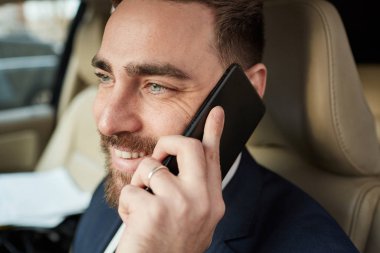 Young happy businessman talking by phone call during driving