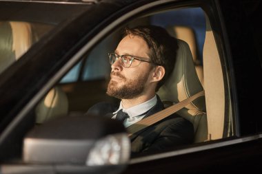 Young driver wearing eyeglasses watching for the road during driving in the car