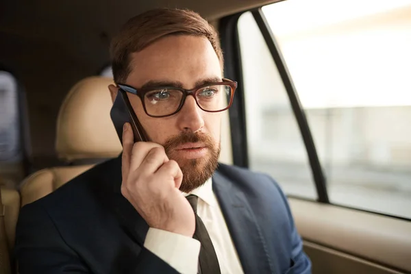 Jovem Barbudo Empresário Óculos Ouvir Alguém Telefone Enquanto Sentado Táxi — Fotografia de Stock